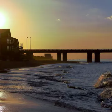 A beach scene with a bridge in the background