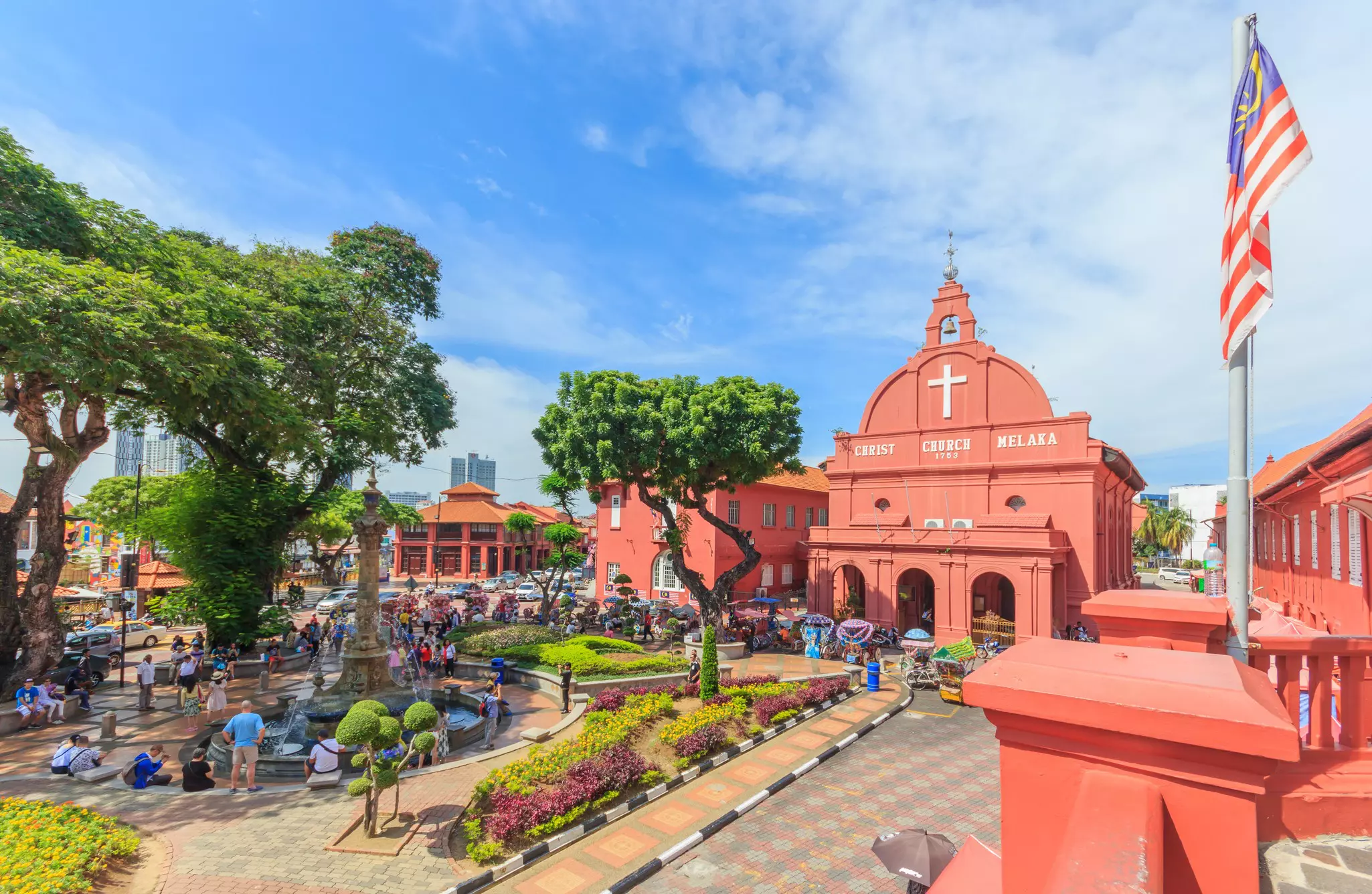 A view of a city square surrounded by red-painted buildings, including a church.