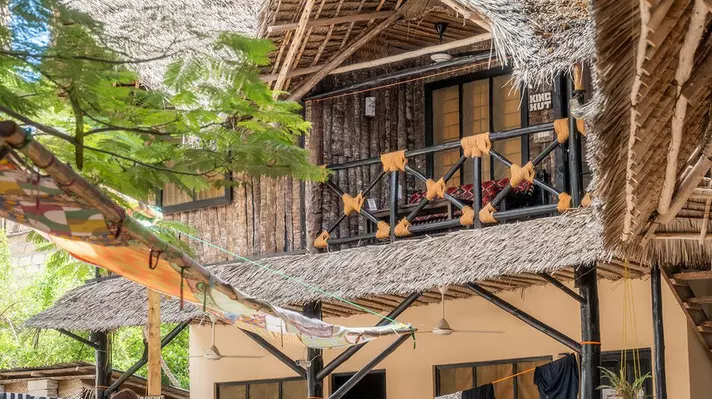 The hut-like exterior of a hostel building with a thatched roof