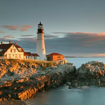 Portland Head Light and keeper's house on golden coastal rocks near Portland, Maine, at sunrise