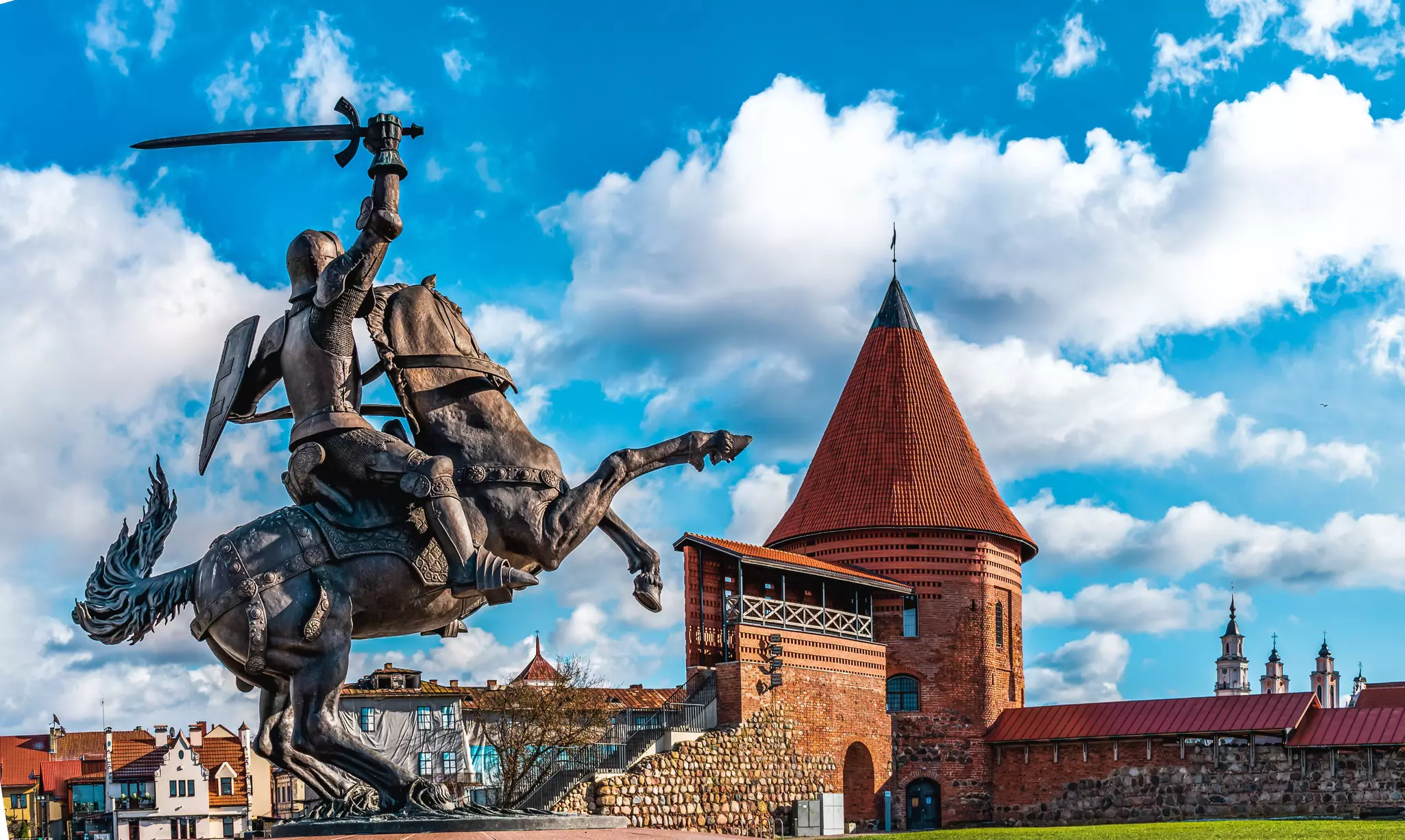 A large statue of a knight on horseback near the round turret of a medieval castle.
