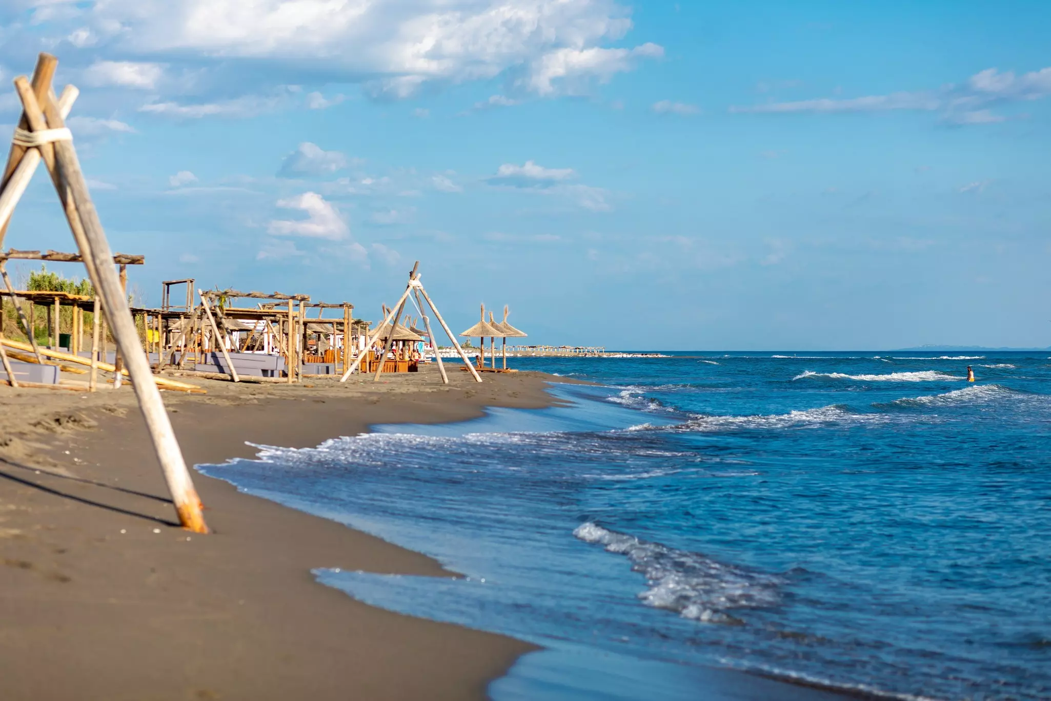 Waves lap a beach, where tripod structures are pictured on the sand.