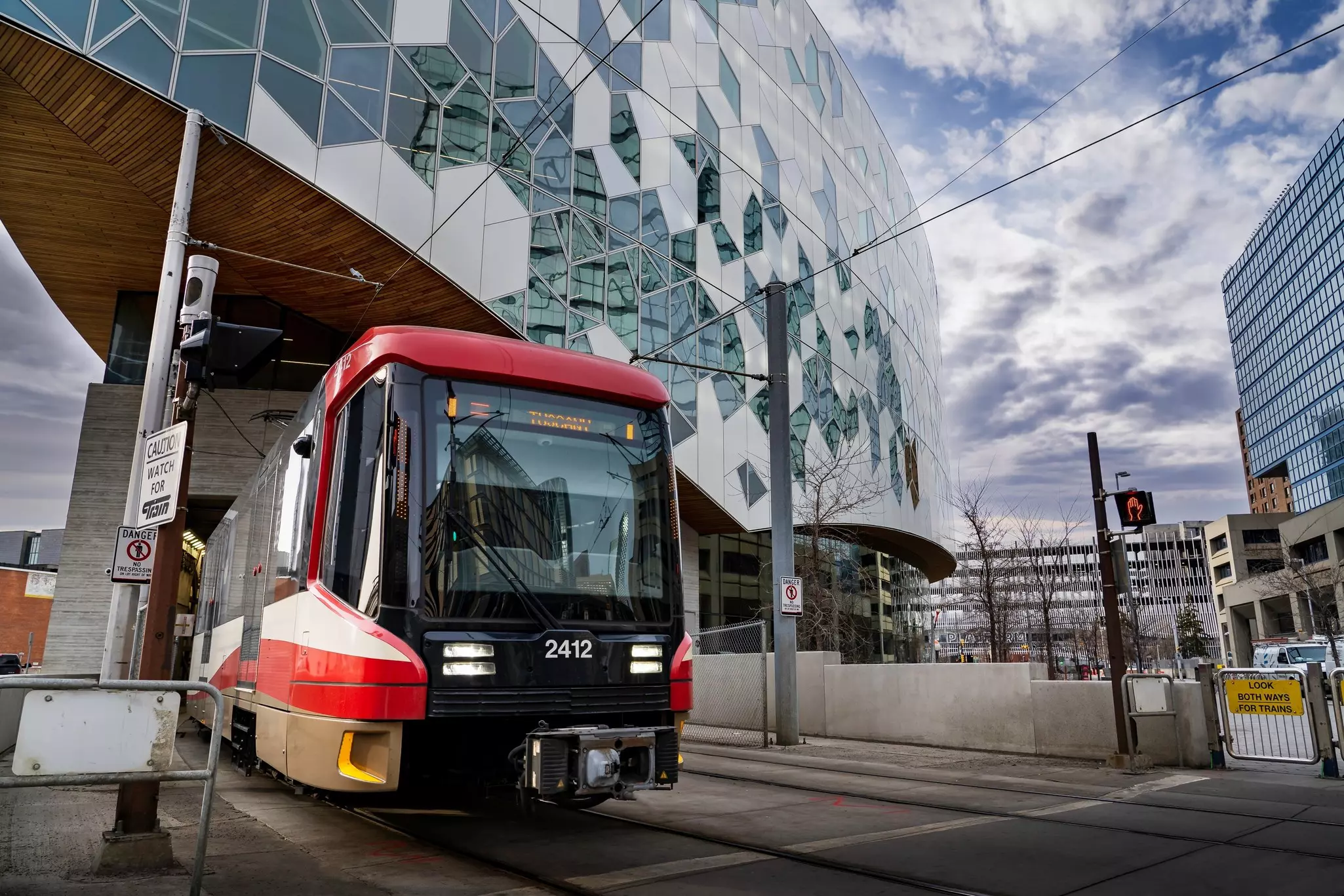 A red tram on a curved track in the dense downtown of a city.