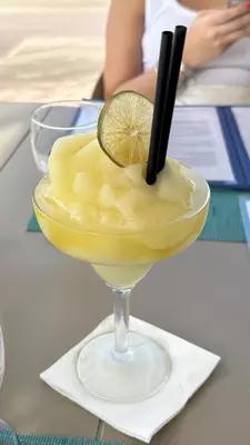 A glass with a yellow iced drink and two straws