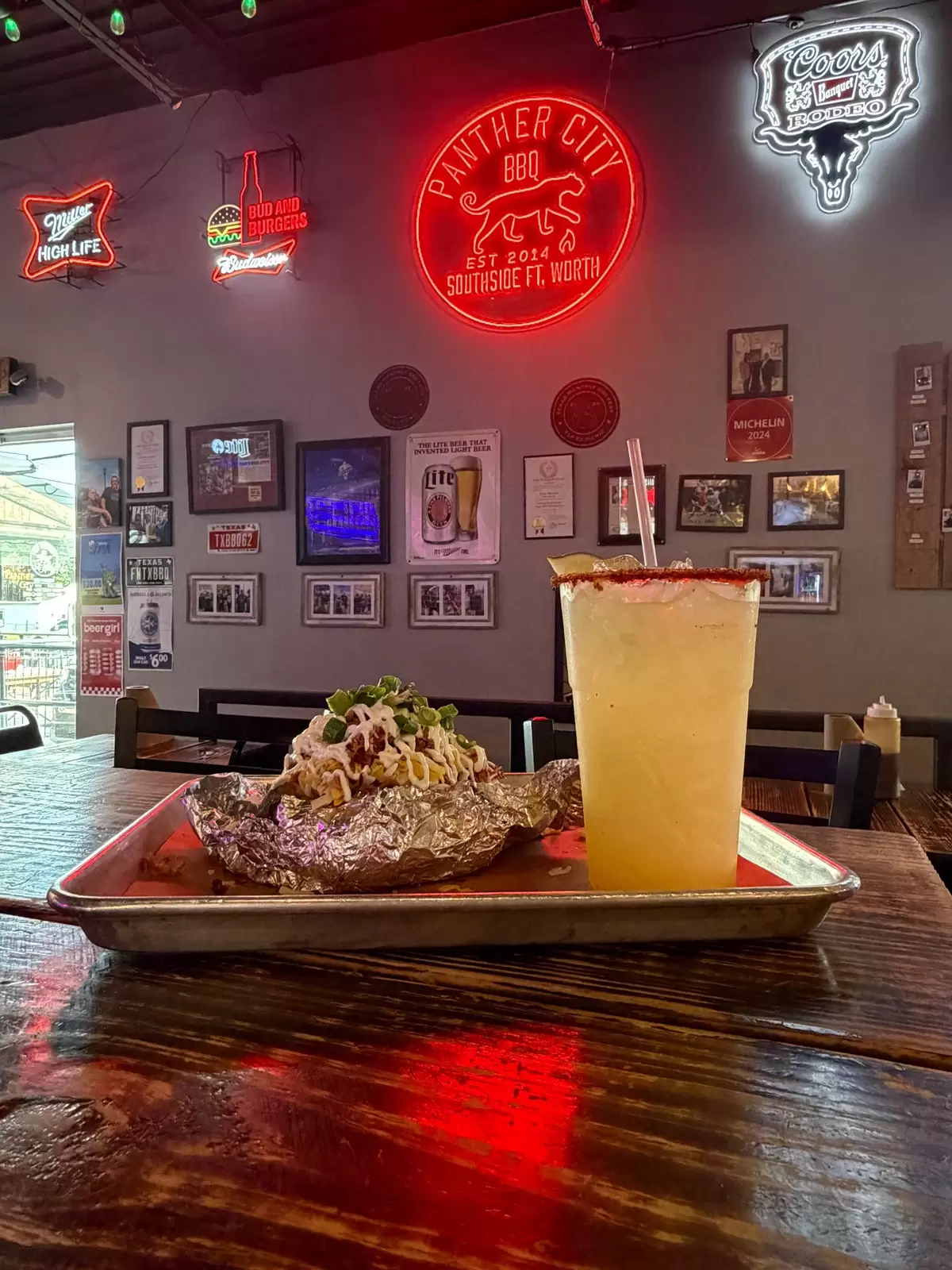 the interior of a barbeque joint with neon lights and food piled high on the table