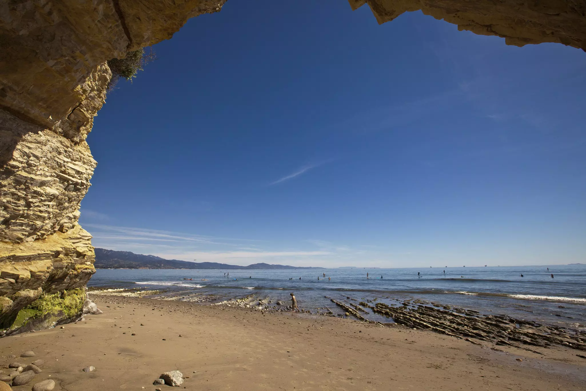 An expansive beach seen through what appears to be a cave opening