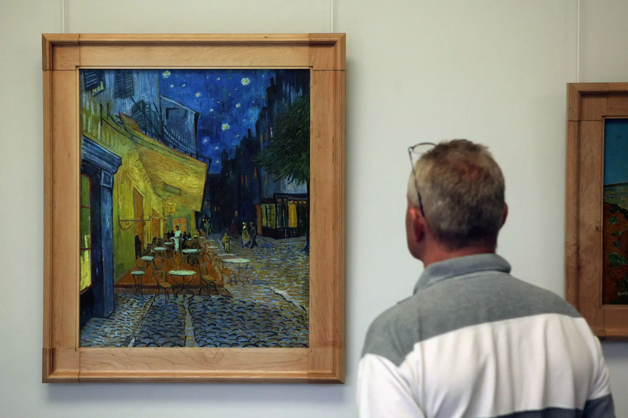 Visitor looks at the painting Cafe Terrace at Night (1888) by Vincent van Gogh in the Kröller Müller Museum. 