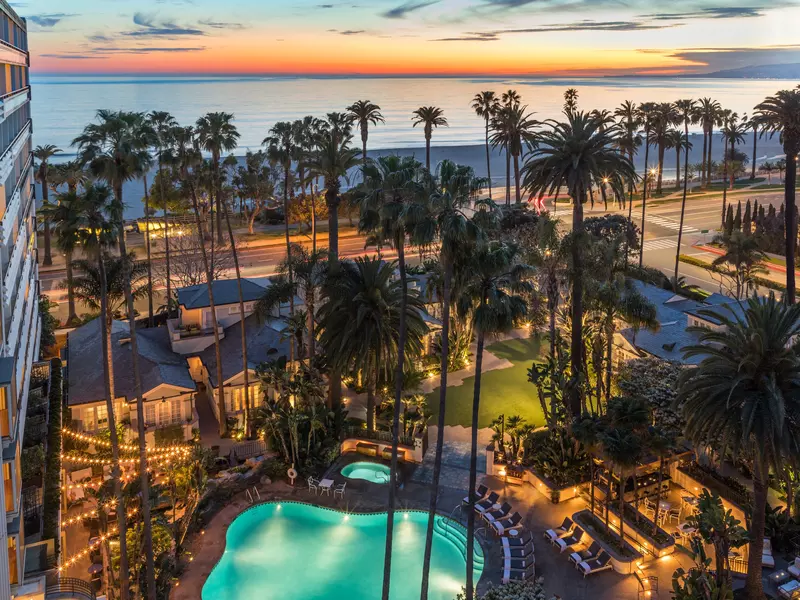 The pool and ocean view at Fairmont Miramar Hotel & Bungalows, bathed in warm, golden light.