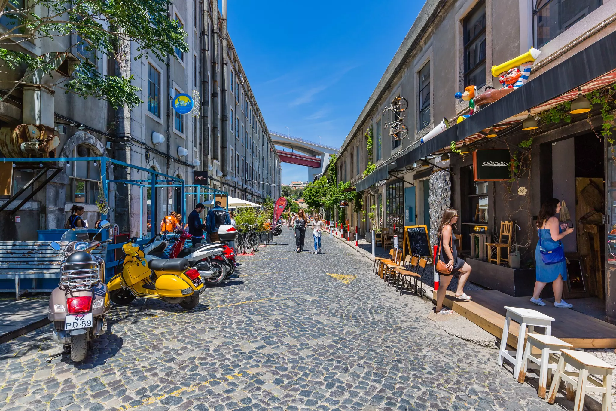 Promenade with shops and cafés at LX Factory located under the Ponte 25 de Abril bridge in Lisbon.