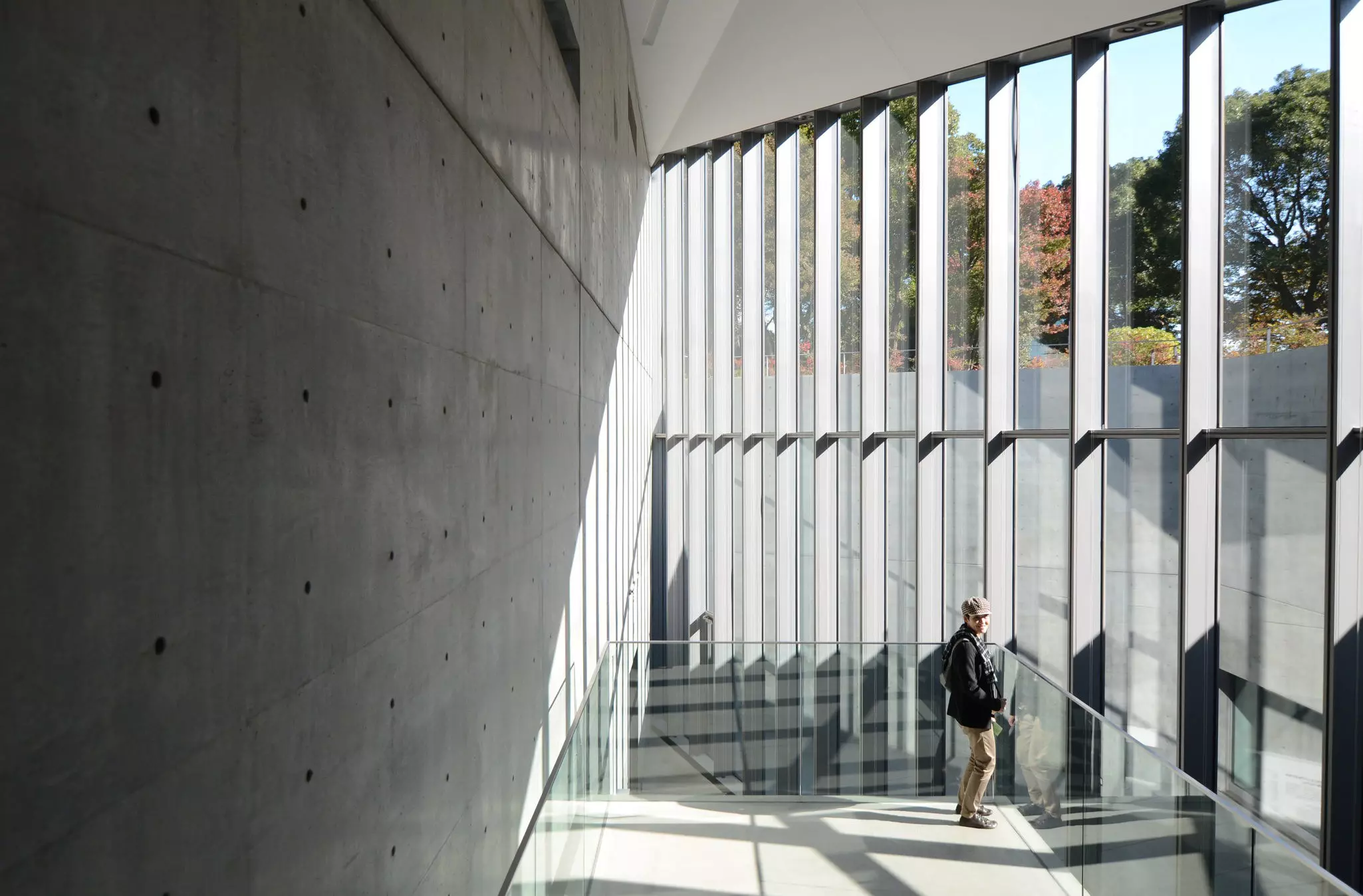 A man on a staircase with floor-to-ceiling windows inside a museum in Tokyo.