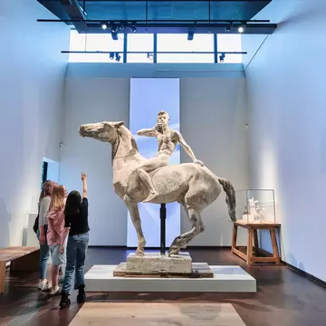 Interior of TID Museum in Odense, Denmark. Group of visitors looking at a sculpture.
