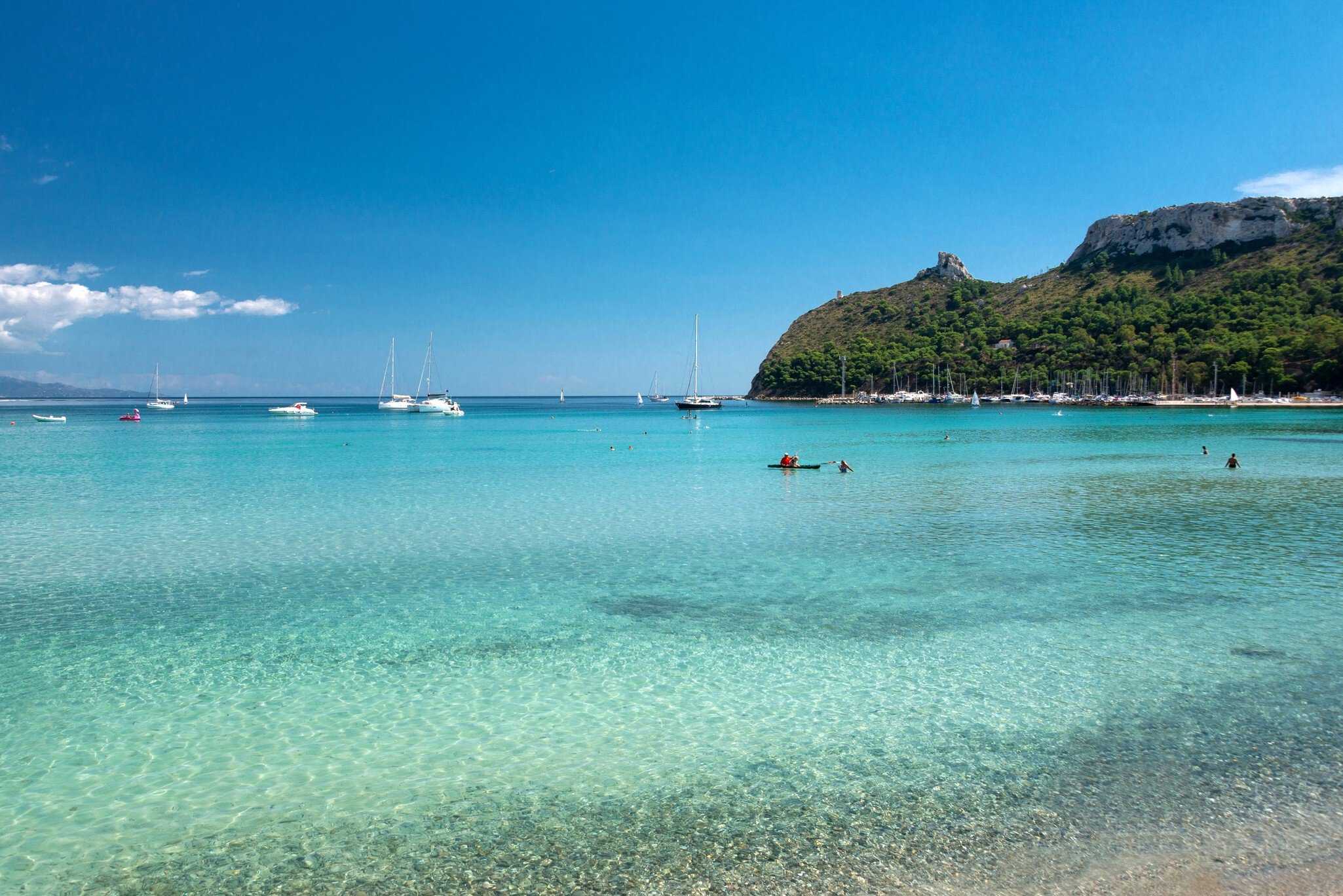 People frolic in the crystal clear waters of Poetto Beach.
