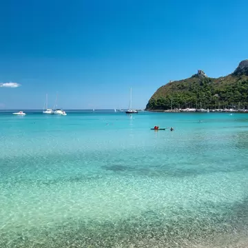 People frolic in the crystal clear waters of Poetto Beach.