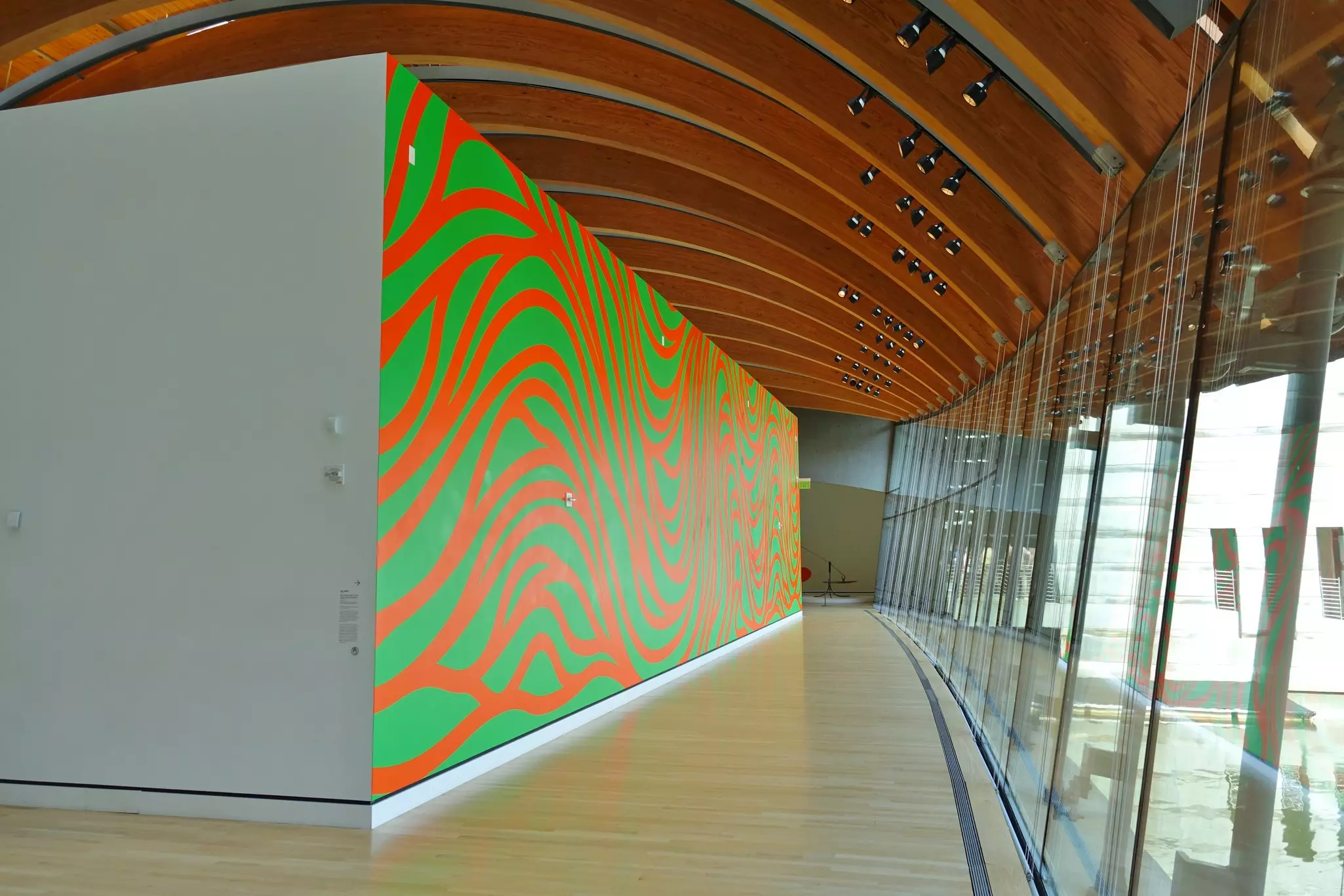 A gallery of an art museum with a bright green-and-orange mural on one wall.