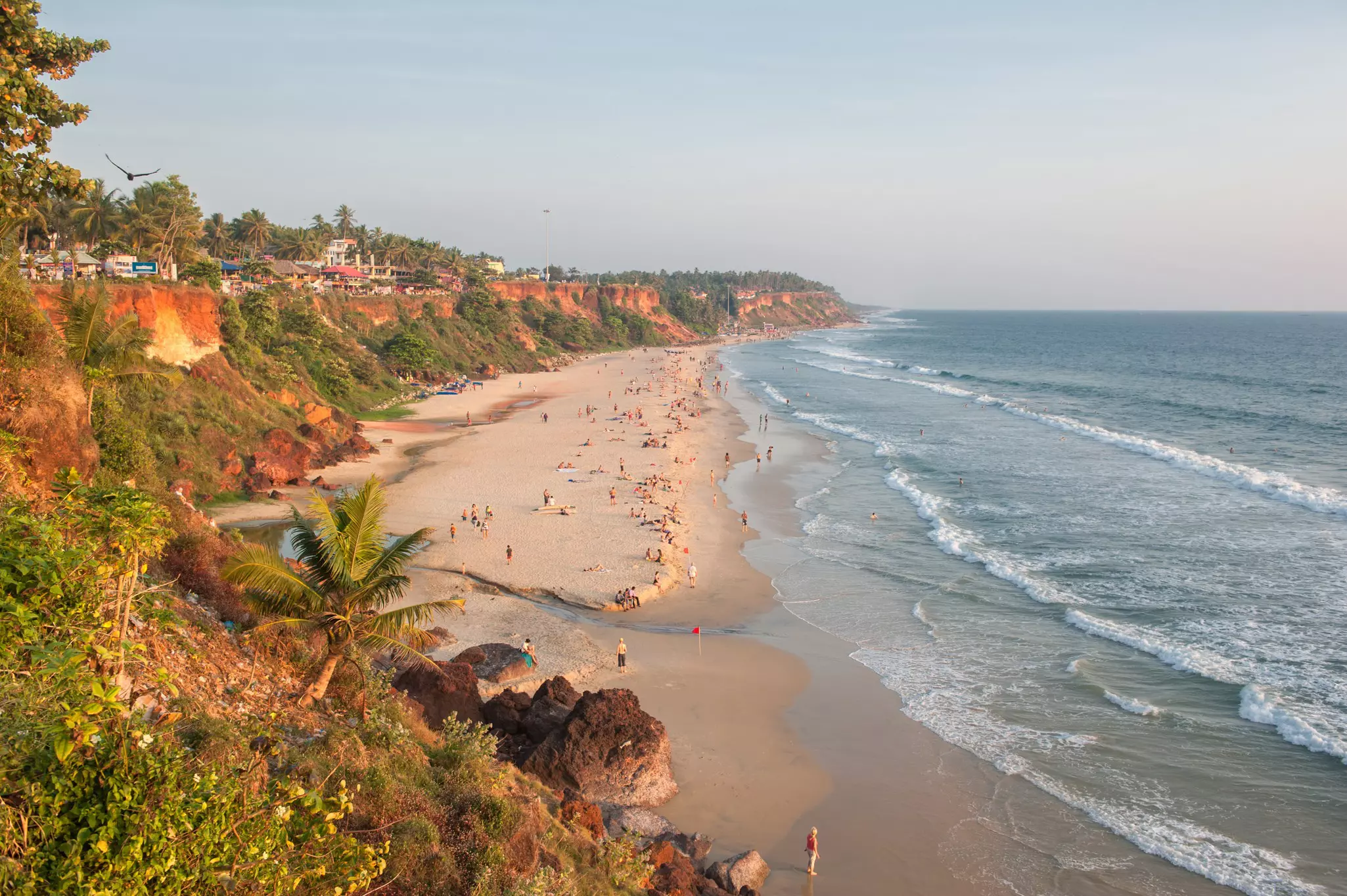 A long stretch of sand backed by cliffs with people sunbathing on it