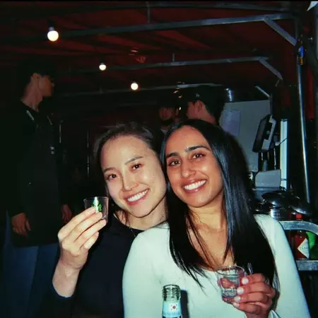 Two women smile and hold glasses of a drink