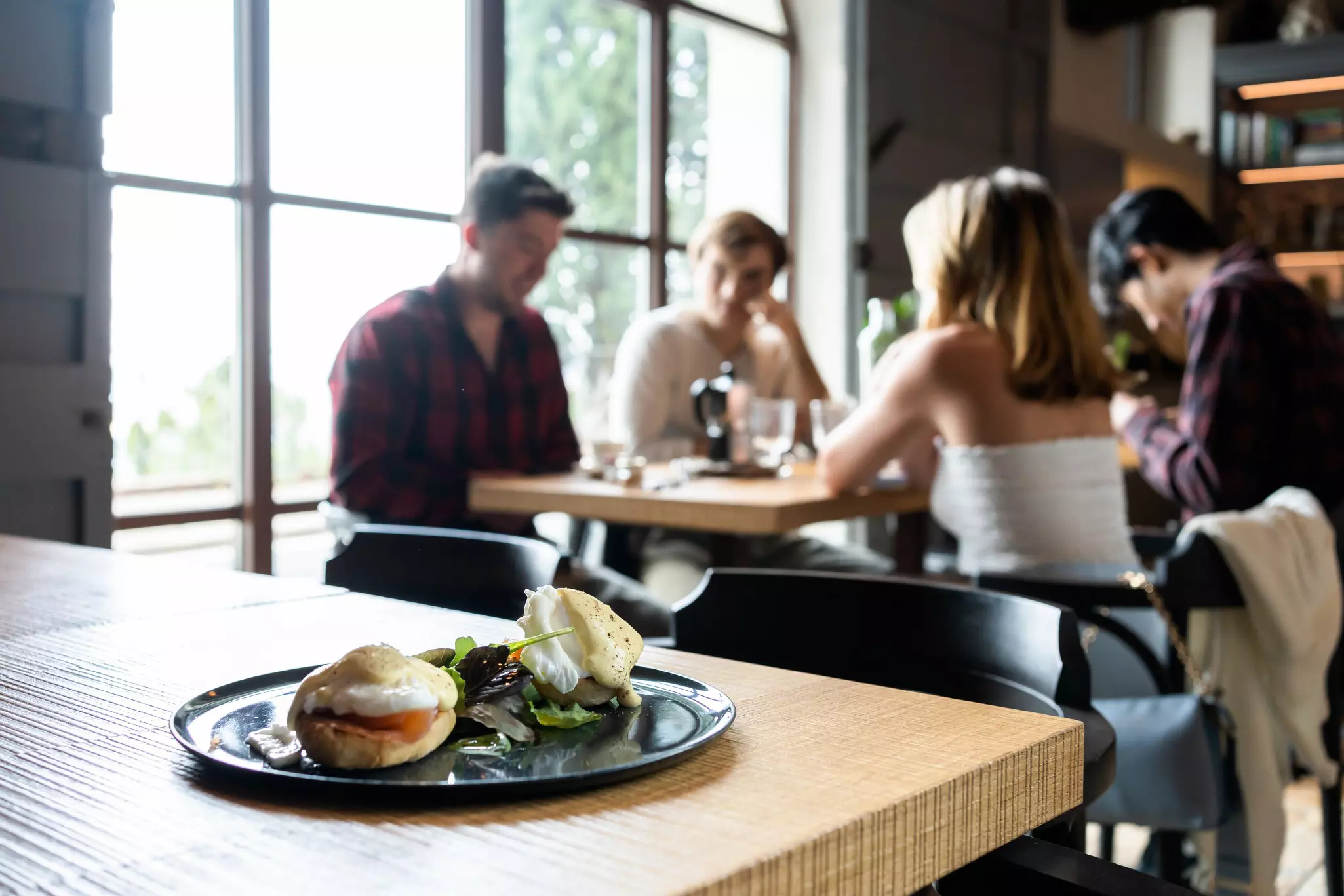 Plate of food on a countertop table with out-of-focus patrons eating at a table in the background.