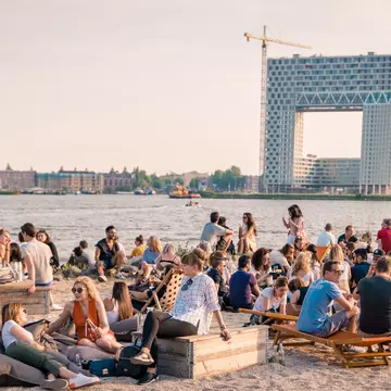 Patrons lounge on a beach at art festival Kinetisch Noord, held at NDSM Wharf. fokke baarssen / Shutterstock