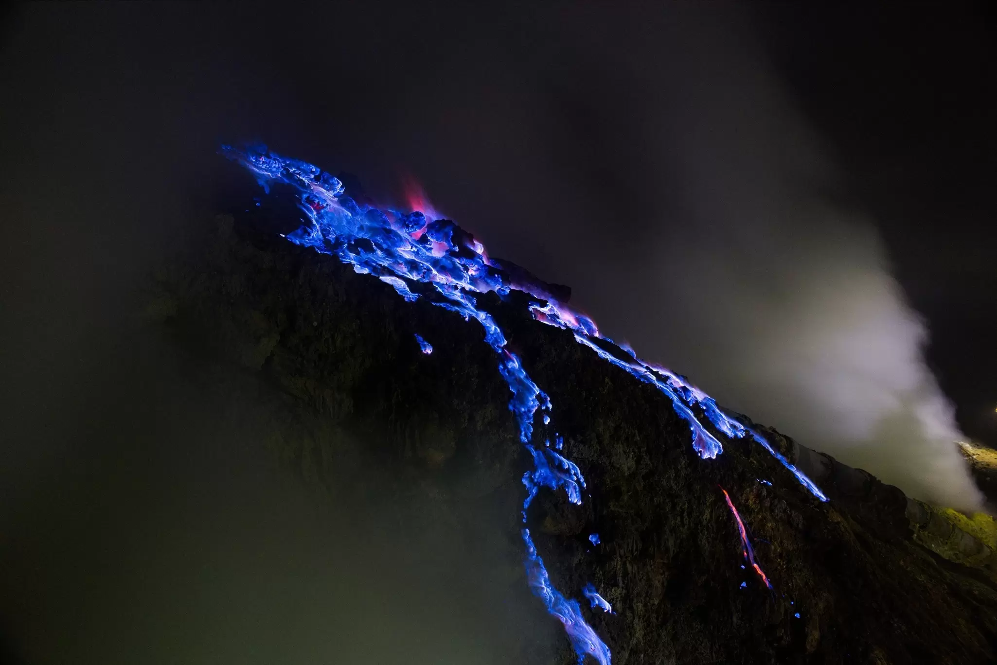 Streams of blue flames caused by sulfur emissions are seen at night on the slope of Kawah Ijen volcano, Java, Indonesia