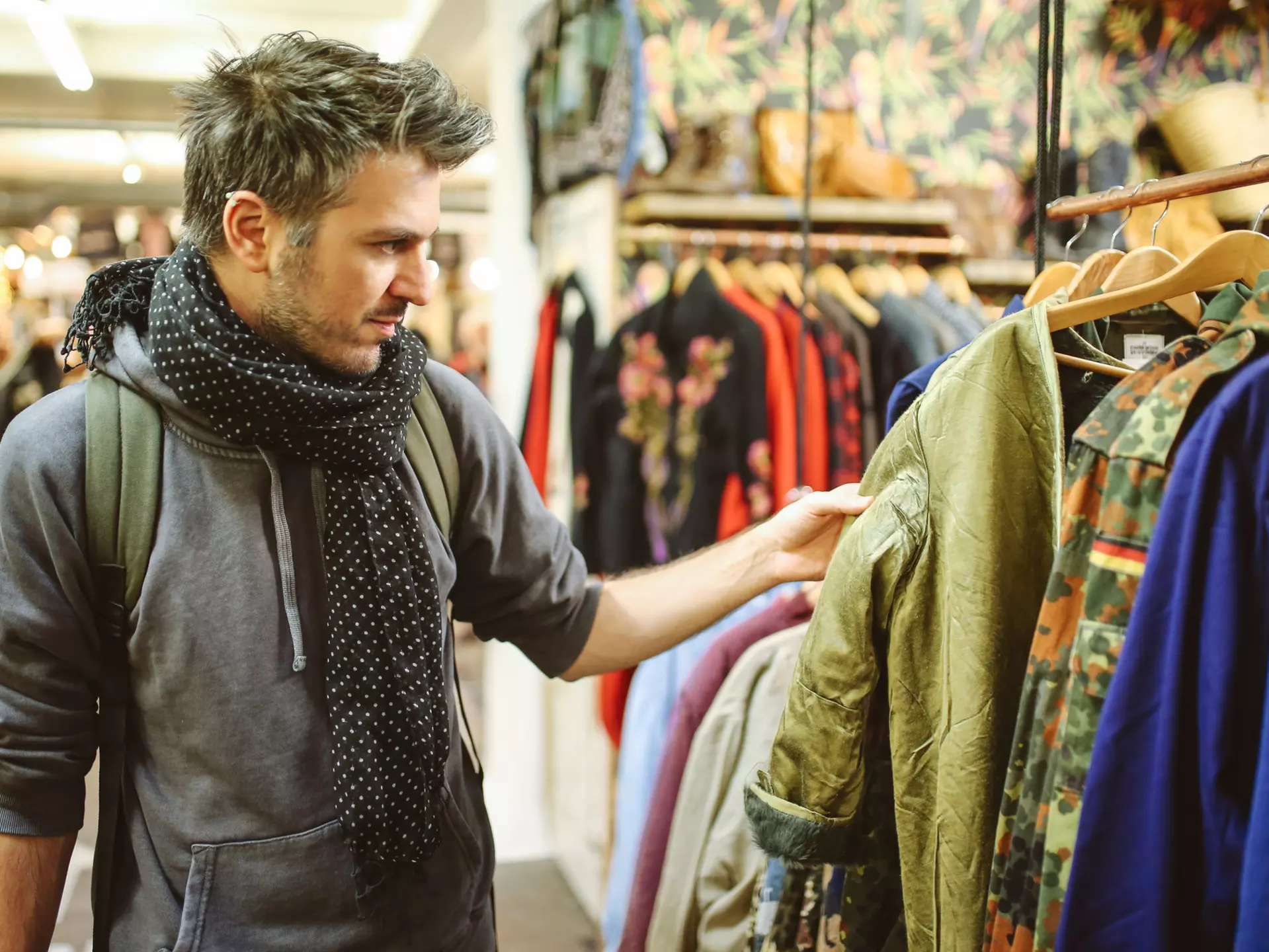 A white man browses through a clothes rail in a second-hand market