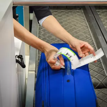 Check-in employee attaches a luggage tag