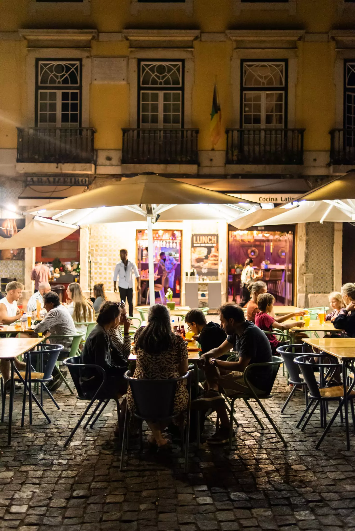 People dining outdoors at night in Alfama in Lisbon, Portugal. 