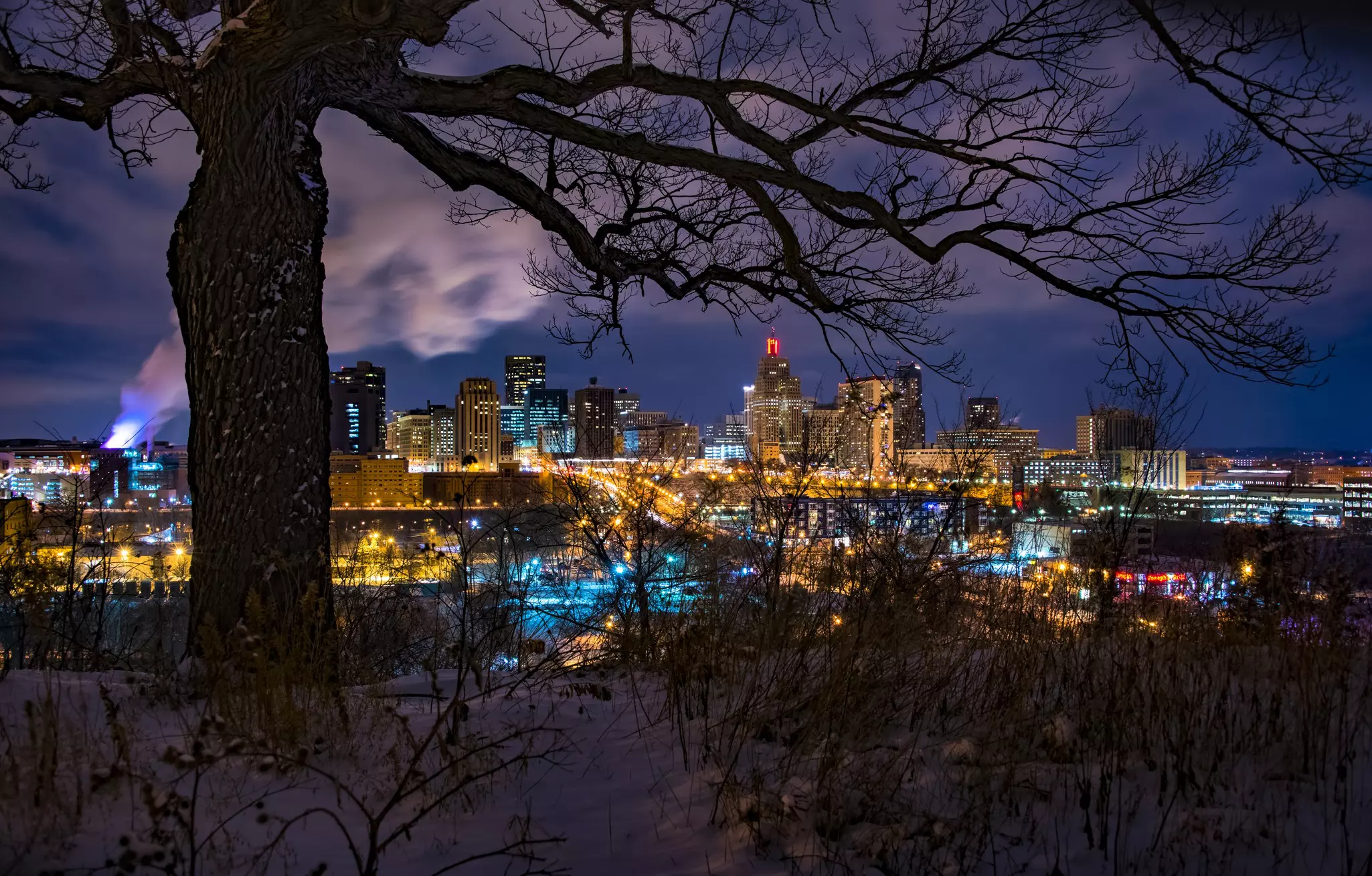 A city skyline at night viewed from a snowy vantage point.