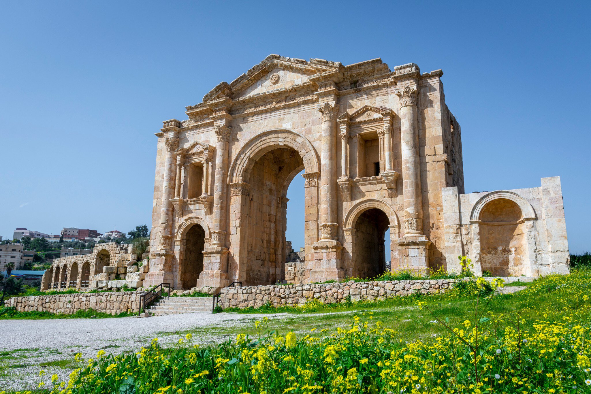 Arch of Hadrian at the roman ruins of Jerash, Jordan. Front view on a sunny day with blue sky. It features some unconventional, possibly Nabataean, architectural features, such as acanthus bases.; Shutterstock ID 1673108263;