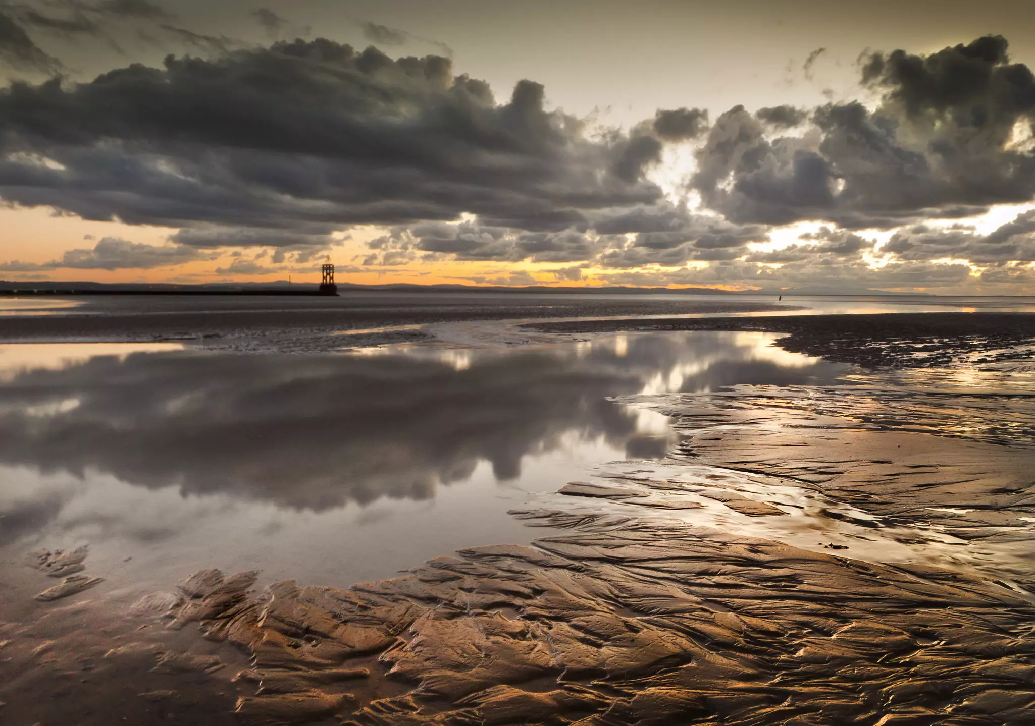 Ripples through sand and a reflection of a cloudy sky