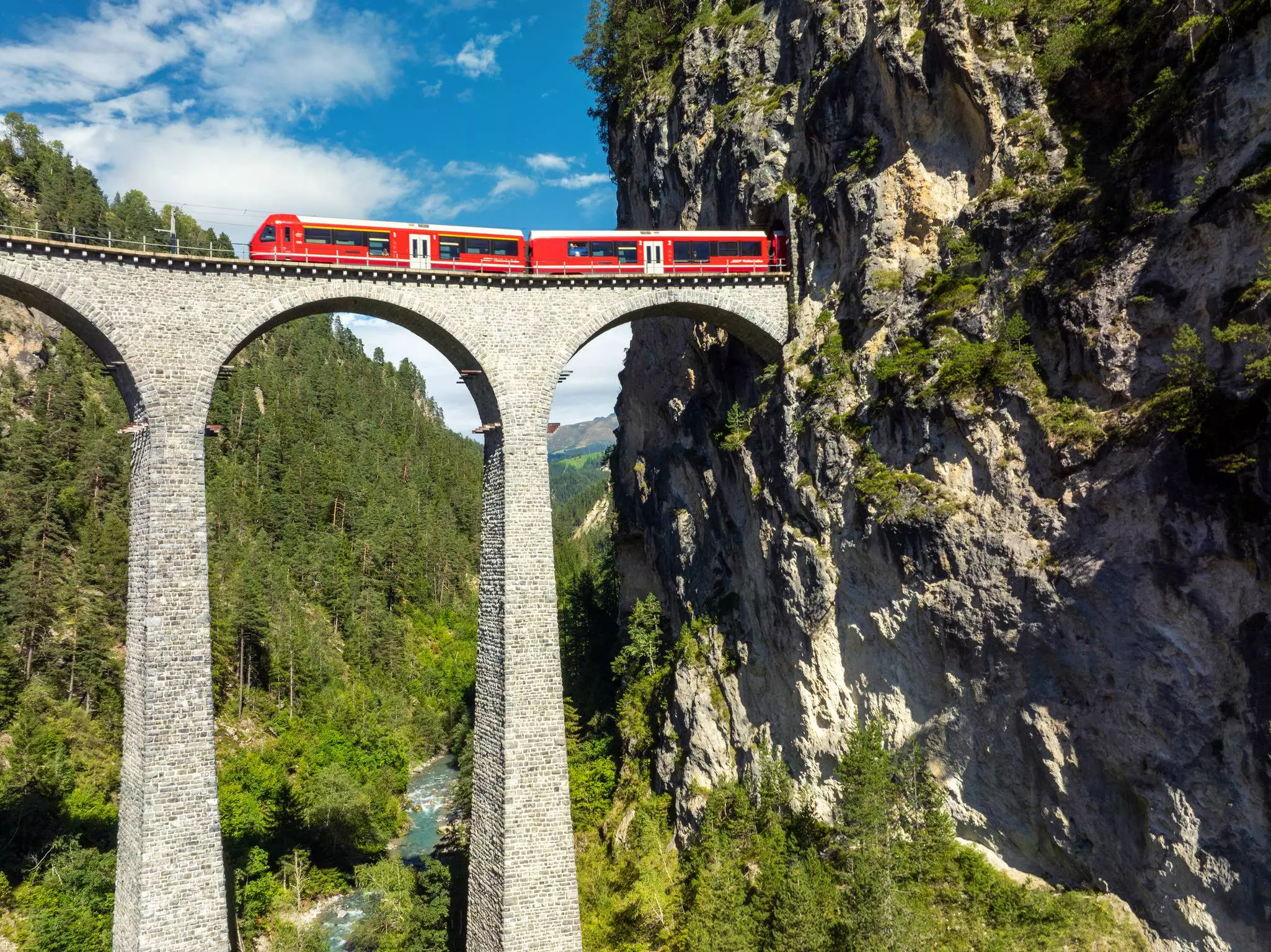 Aufnahme eines Zuges der RhB auf dem Landwasserviadukt mit hohen Steinbögen. Die Brücke spannt sich zwischen steilen Felswänden.
Filisur, Landwasser Viaduct