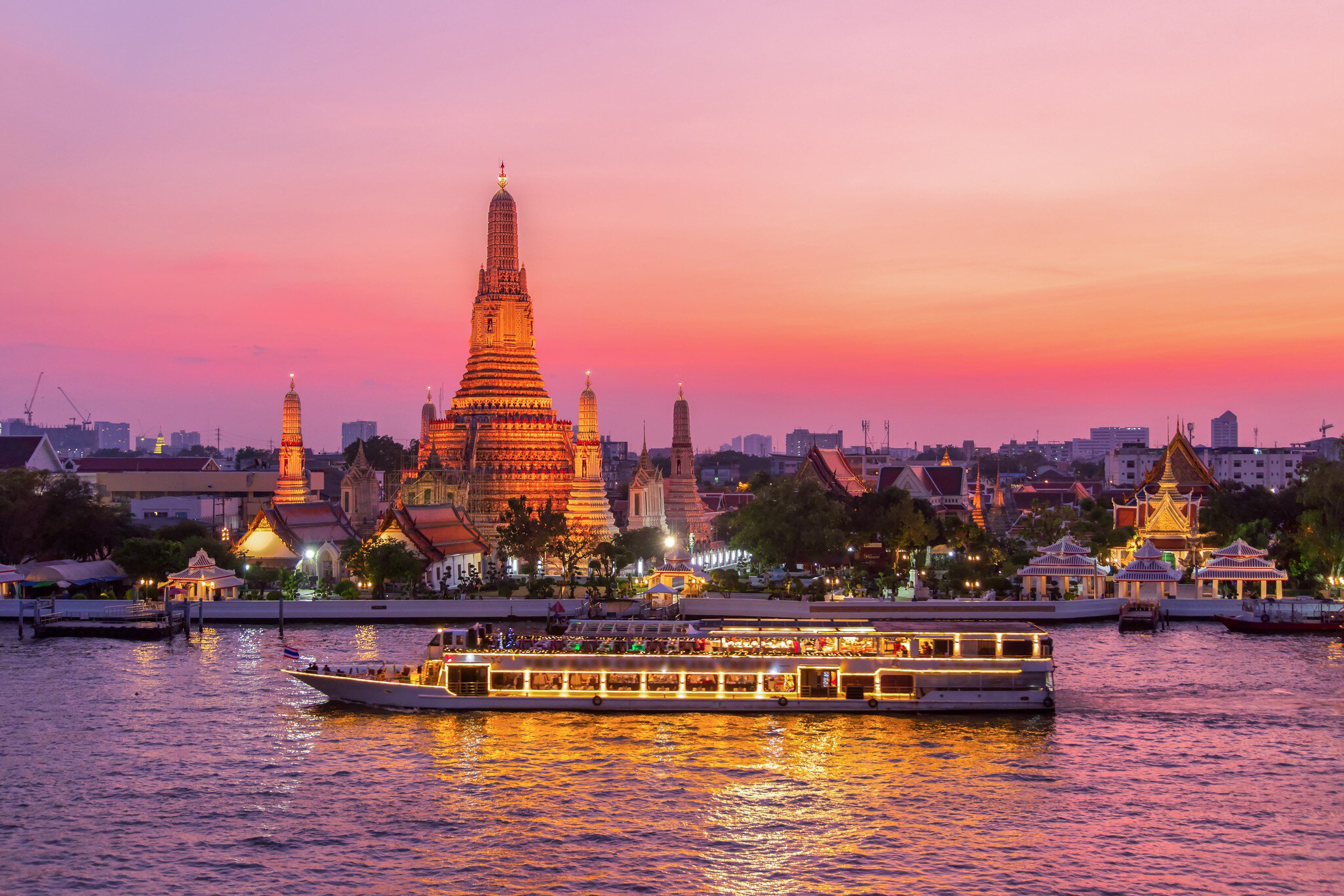 River cruise boat passes a stupa under the soft glaze of an apricot-colored sunset
