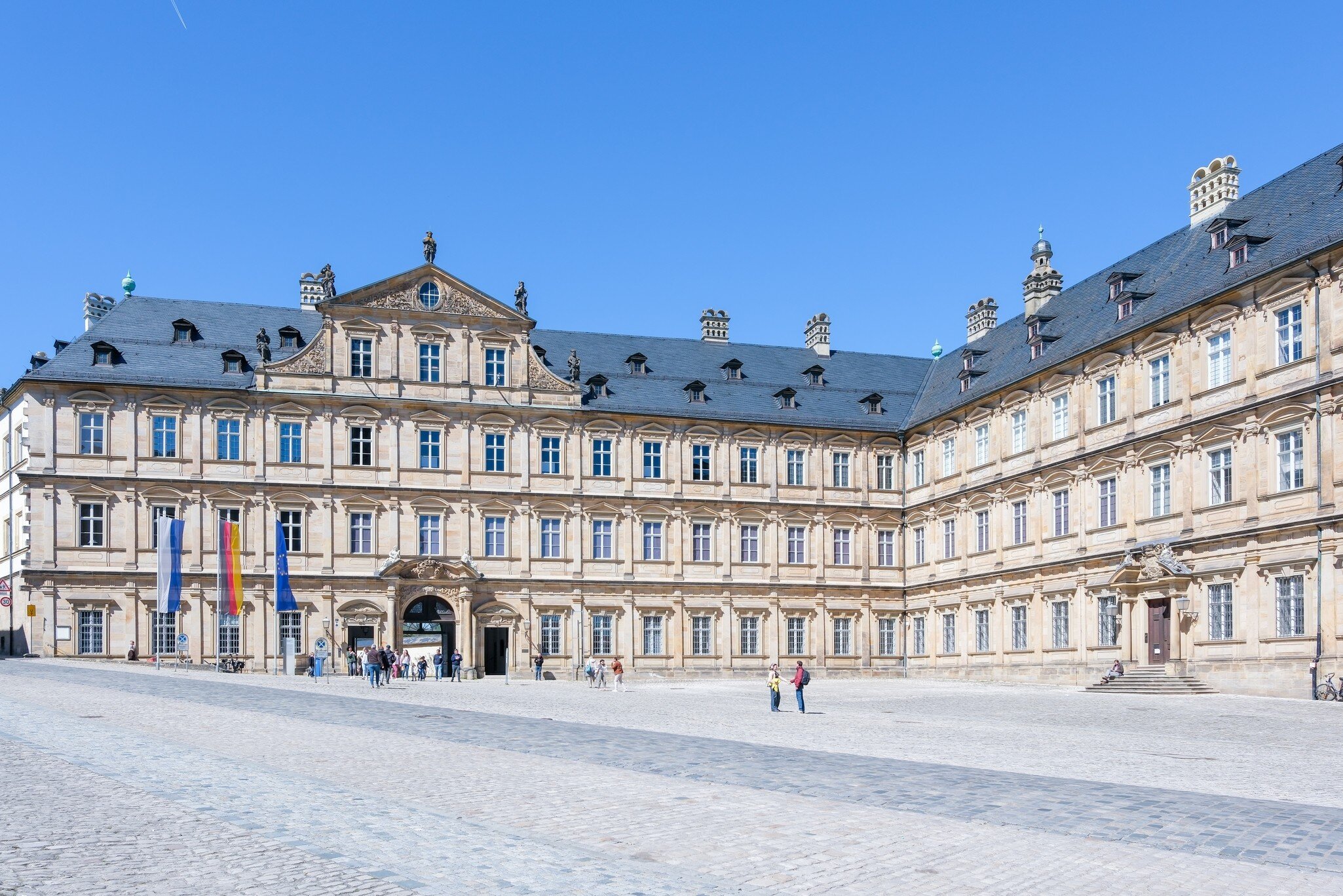 Visitors walk around Neue Residenz in Bamberg, Germany.