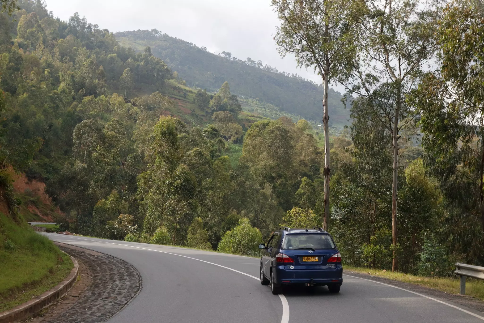 A car climbing a green mountain road on RN4, just North of Kigali, Rwanda  