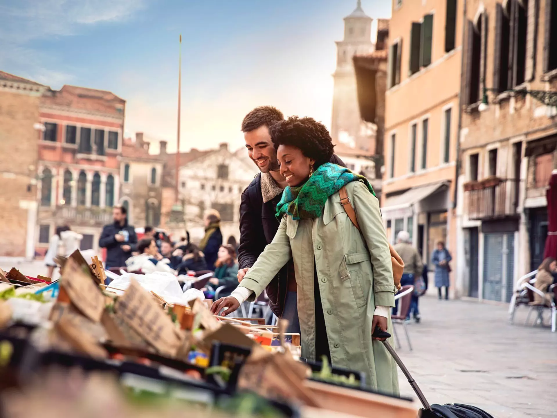 A woman and man shop at a stall in historic Venice.