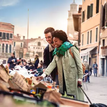 A woman and man shop at a stall in historic Venice.