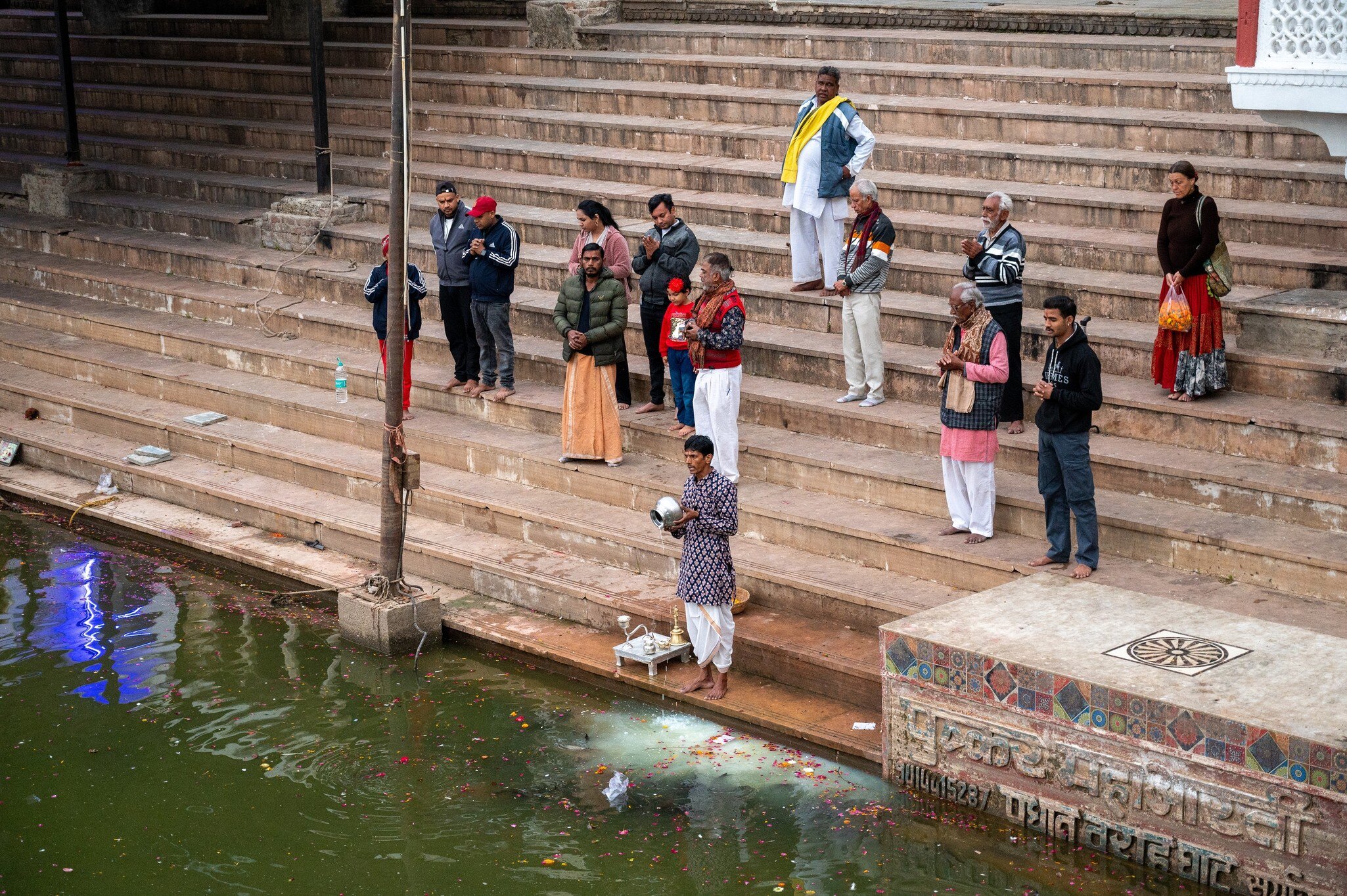 Priest pouring milk into lake during evening worship at Varah Ghat on Pushkar Lake, performing evening worship as lamps glow and prayers echo along the sacred water. 