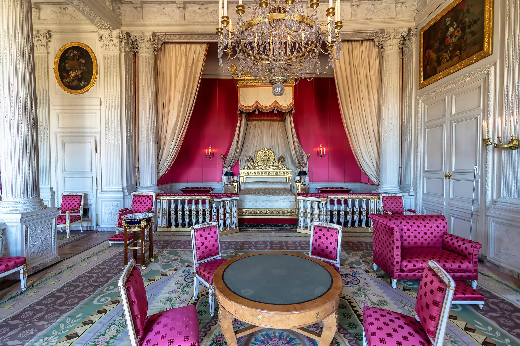 A bedroom in a palace with bright pink upholstered furniture and curtains.