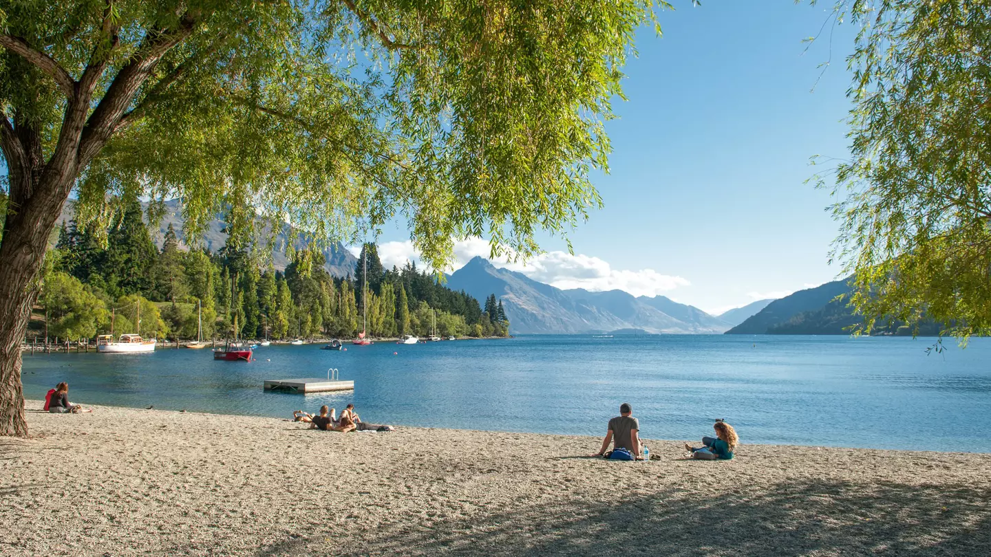 Visitors relax on the shore of Lake Wakatipu in Queenstown