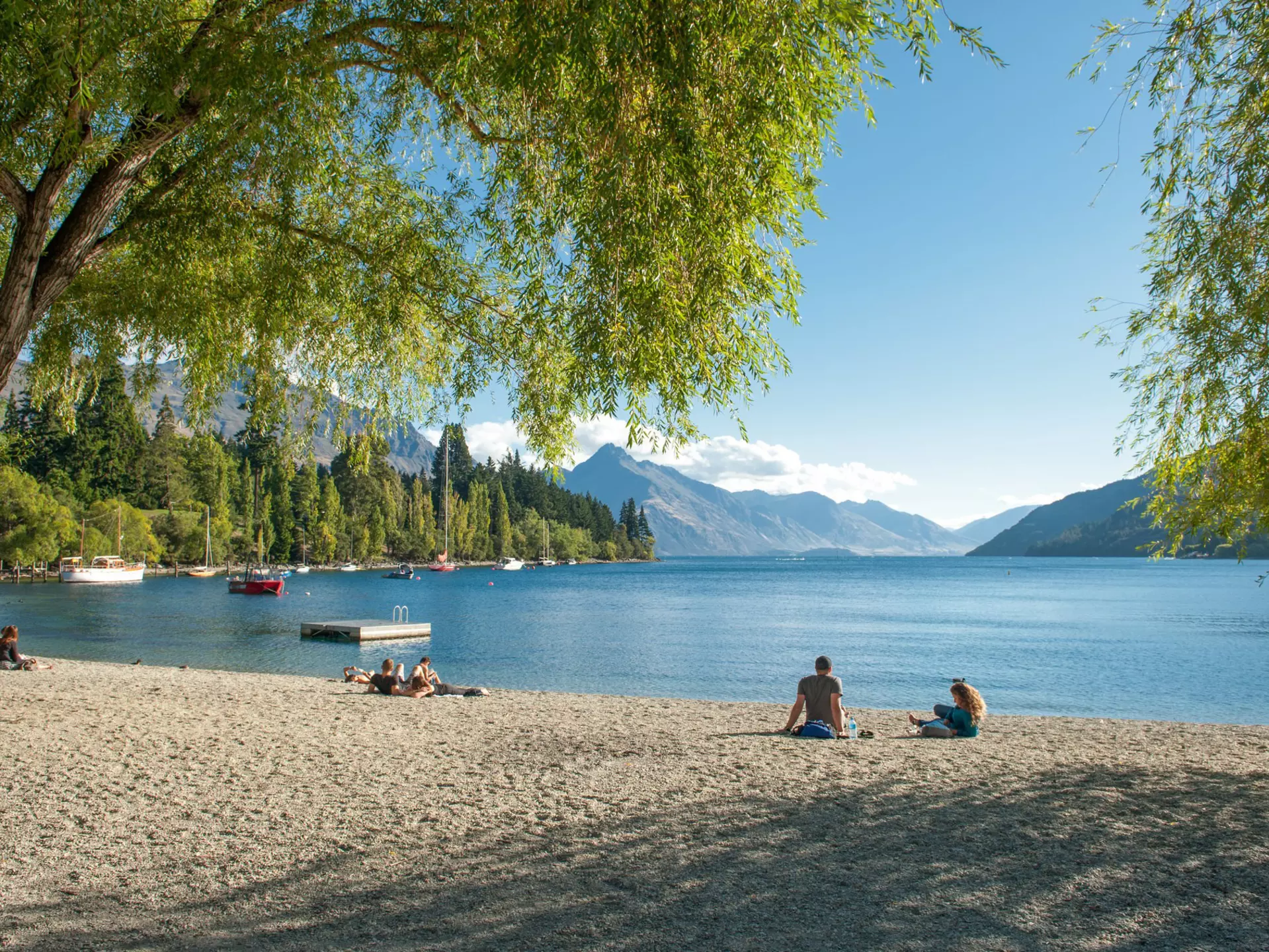 Visitors relax on the shore of Lake Wakatipu in Queenstown