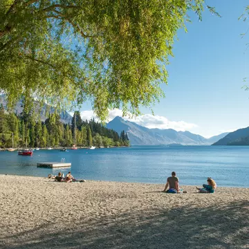 Visitors relax on the shore of Lake Wakatipu in Queenstown