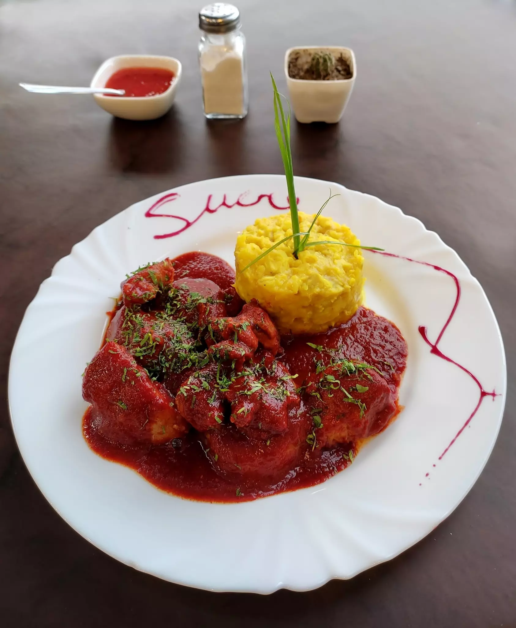 Bolivian pork dish Mondongo. The meat is stewed in a sweet paprika sauce served alongside two starches, potatoes and corn