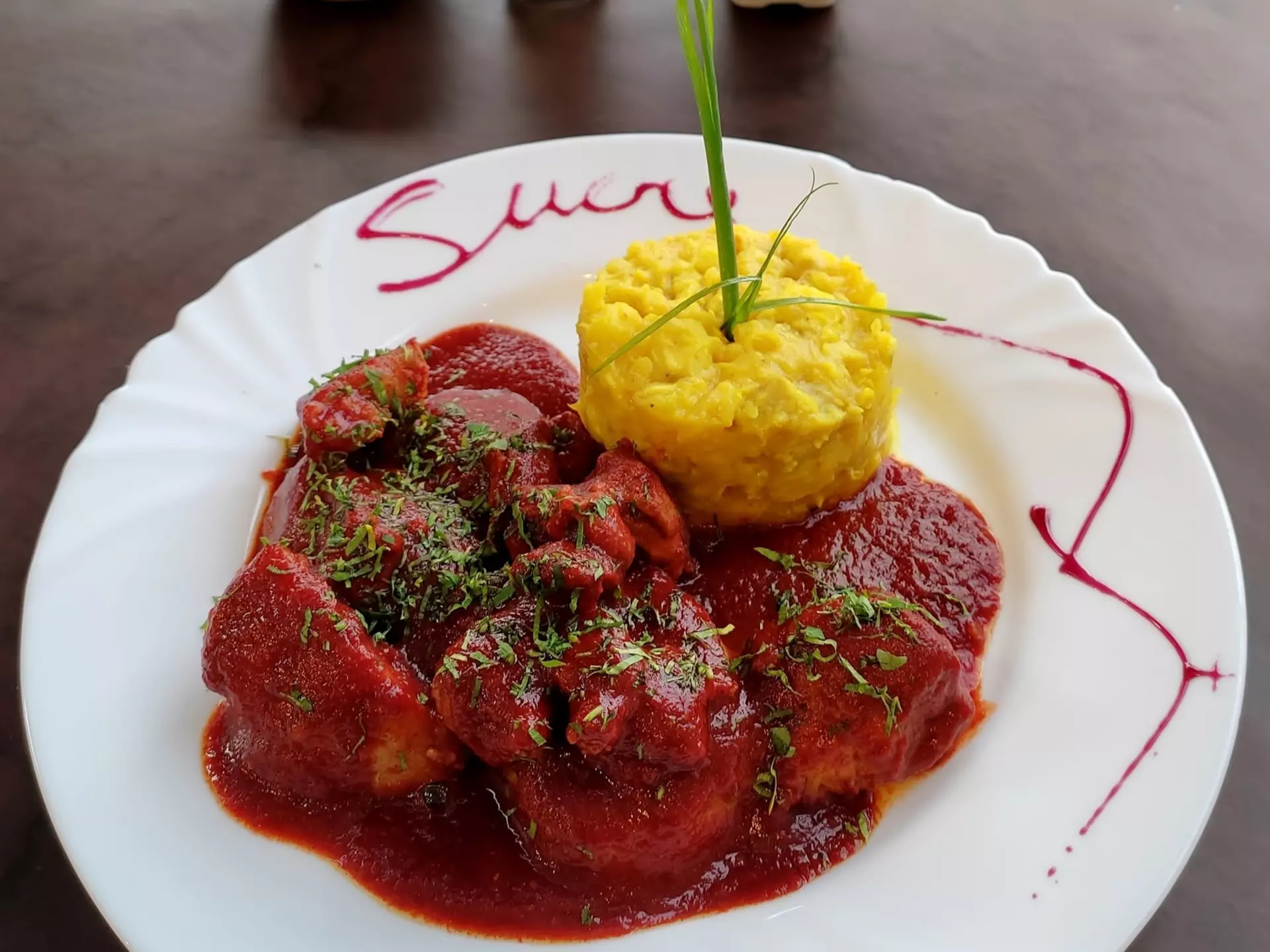 Bolivian pork dish Mondongo. The meat is stewed in a sweet paprika sauce served alongside two starches, potatoes and corn