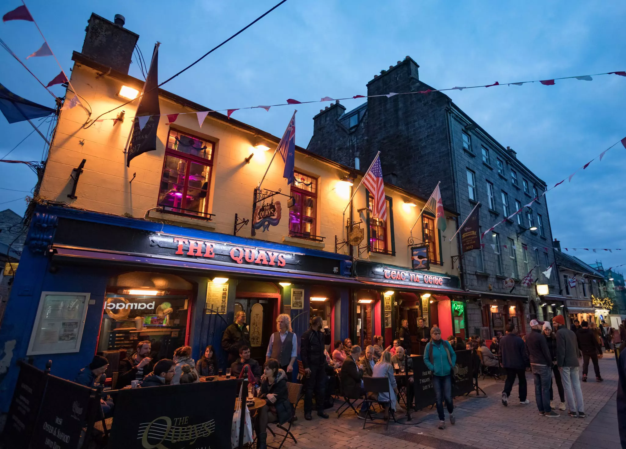 People on tables outside the Quays Bar and Restaurant at night. The restaurant is on Quay Street in the Latin Quarter of Galway.