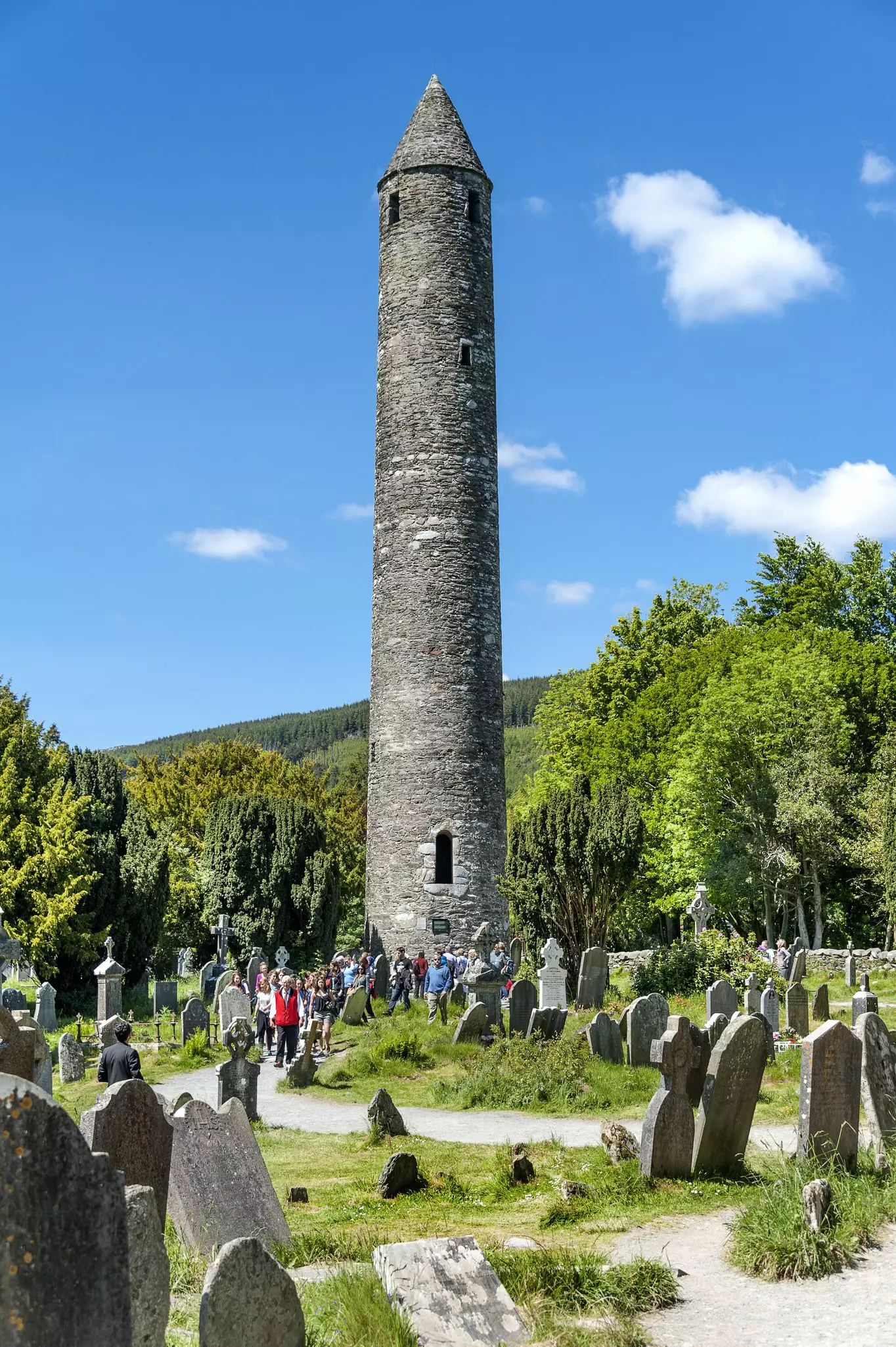Steps going up to a stone arch with a forest and stone Celtic cross in the background