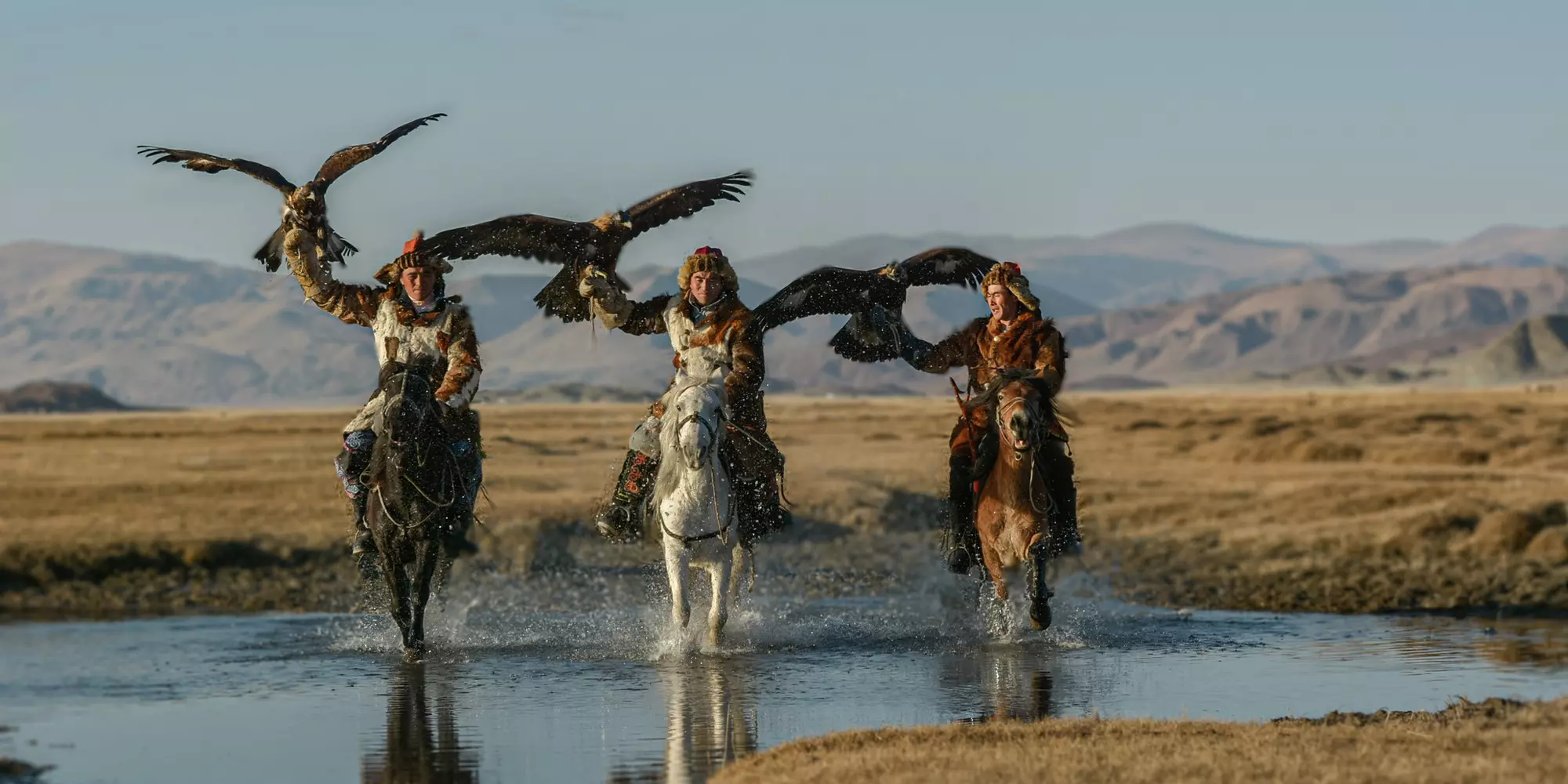 Mongolian eagle Hunters in traditionally wearing typical Mongolian Fox dress culture of Mongolia on Altai Mountain background at Ba-yan UiGII, MONGOLIA