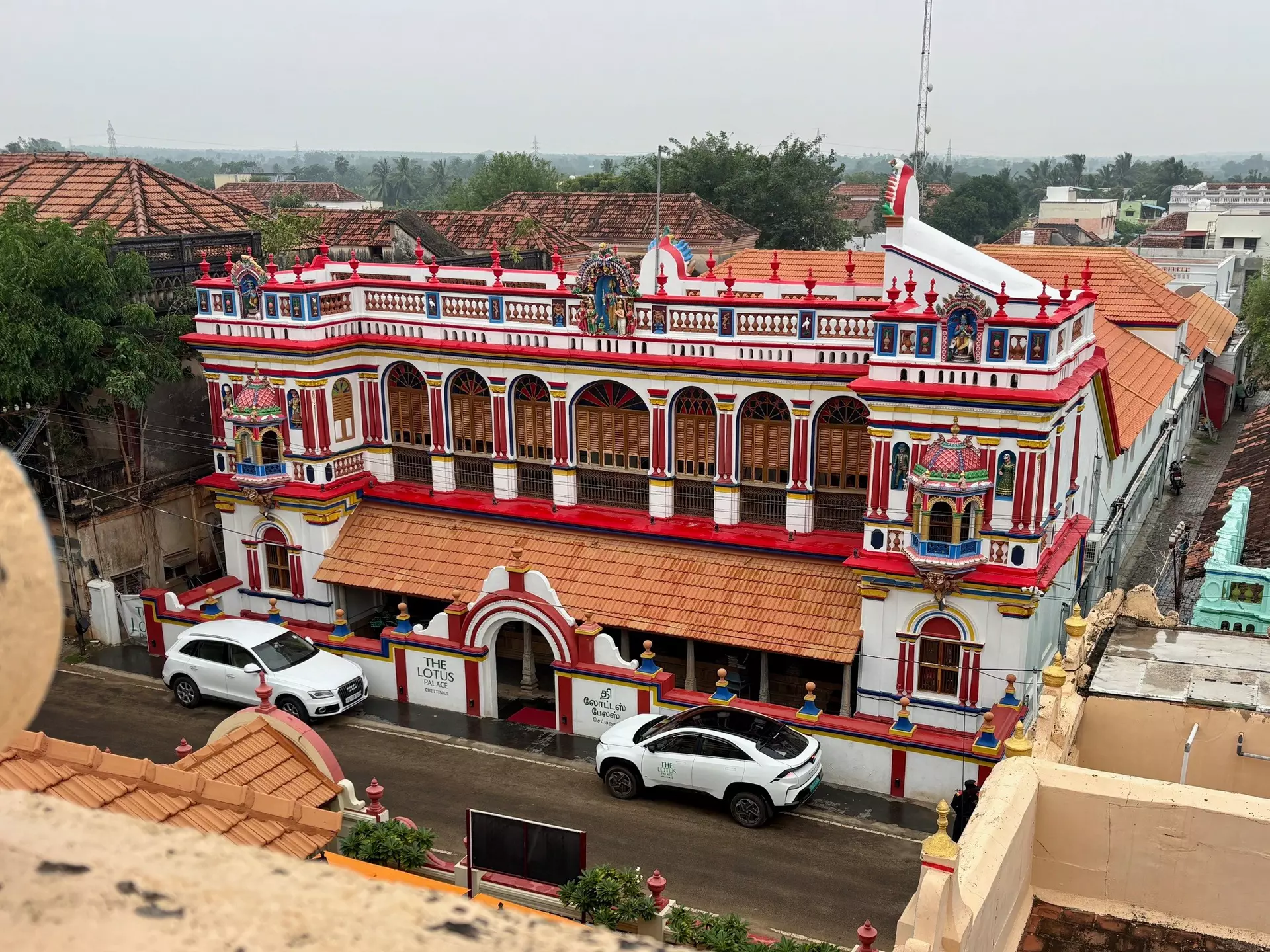 An overview of a brightly painted, architecturally elaborate mansion in a village.