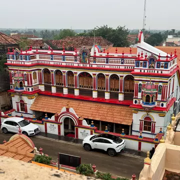 An overview of a brightly painted, architecturally elaborate mansion in a village.