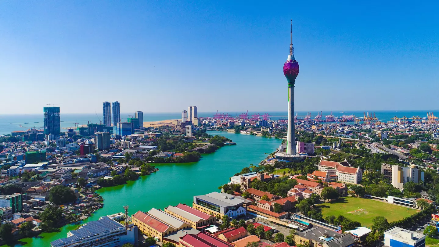 A cityscape with a tall modern TV tower and a river flowing to the sea.