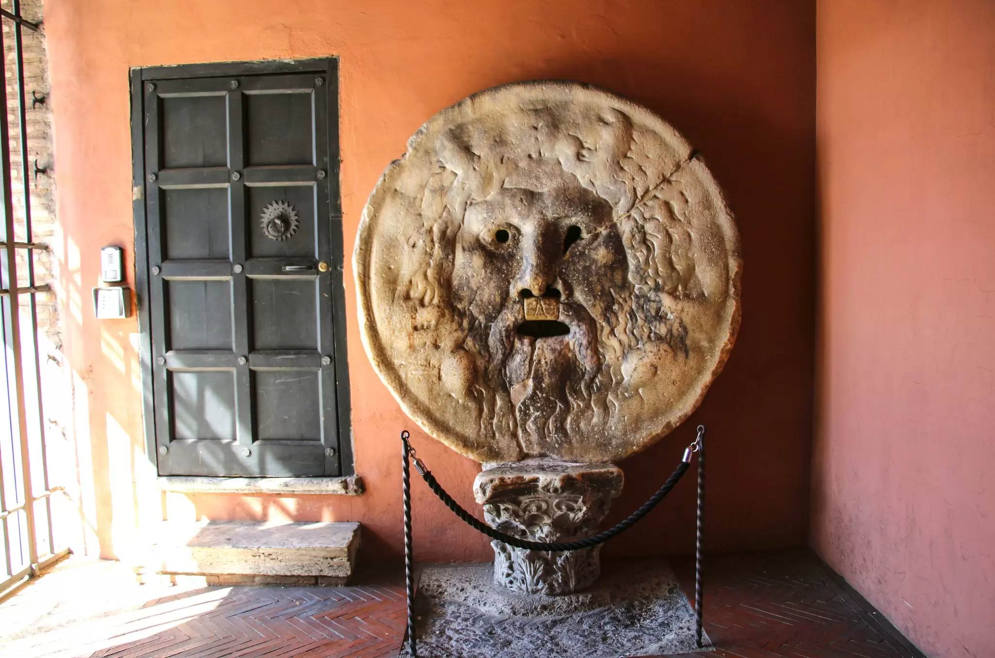 A round stone with a carving of a lionlike face.