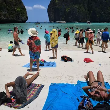 Tourists sunbathing and walking on Maya Bay